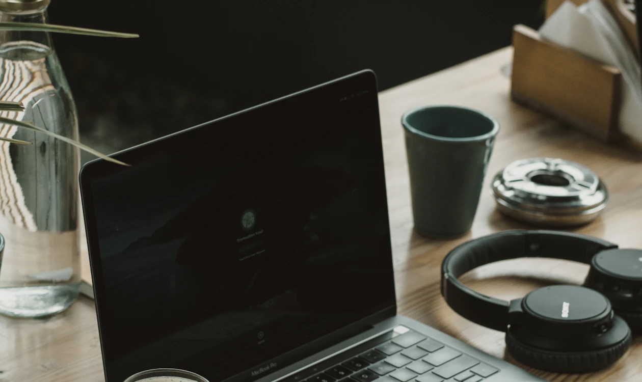 Laptop, headphones, and coffee on a wooden desk
